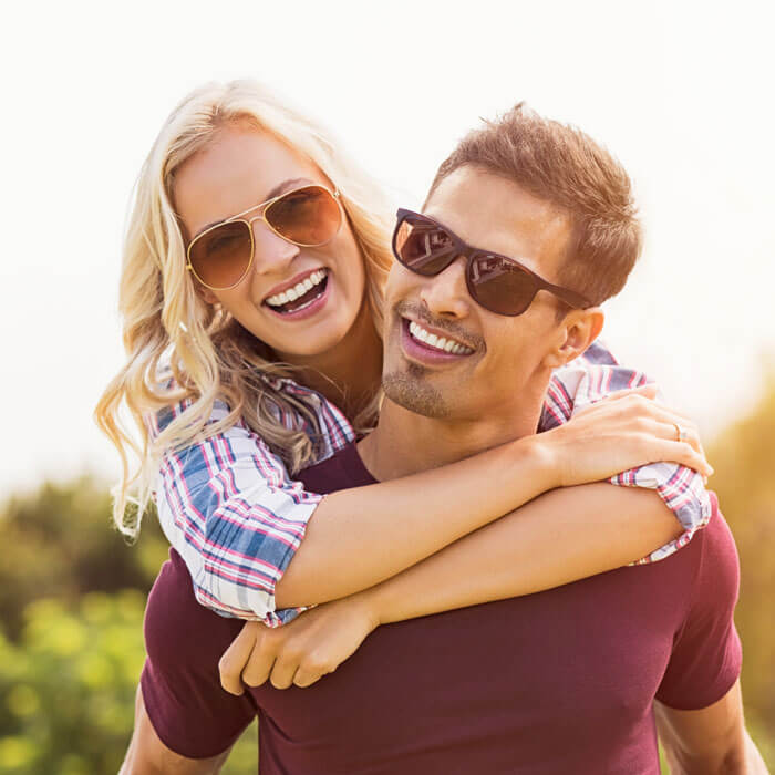man and woman both wearing sunglasses outdoors and smiling
